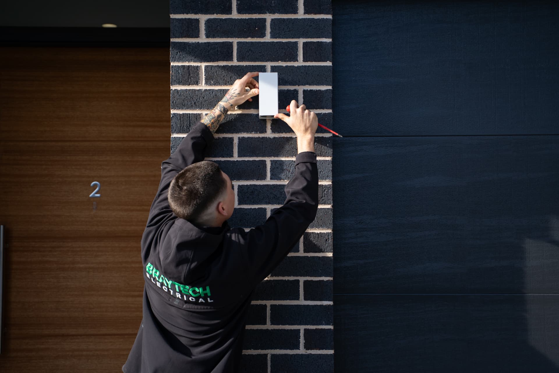 Braytech electrician installing an exterior light